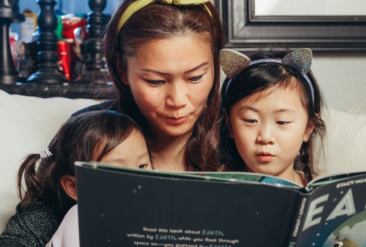A parent reading a book together with two children